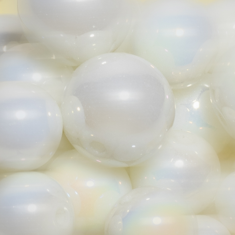 A close-up of luminous, iridescent pearl-like spheres grouped together, reflecting soft light.